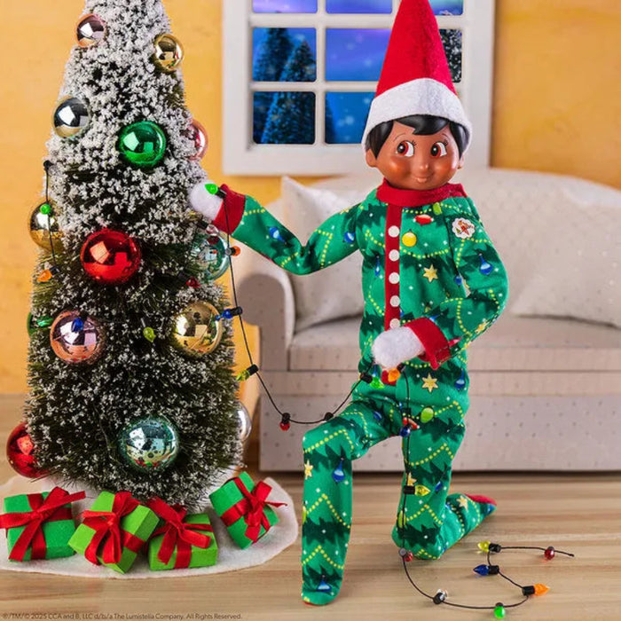 Elf on the Shelf in a festive outfit decorating a Christmas tree.