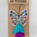 A butterfly-shaped air freshener with a decorative tassel hanging from it.
