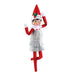 Elf on the Shelf character in a tinsel dress and a  green bow on a white background