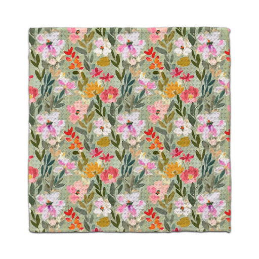 A floral napkin featuring a pattern of green, pink, and yellow flowers on a white background.
