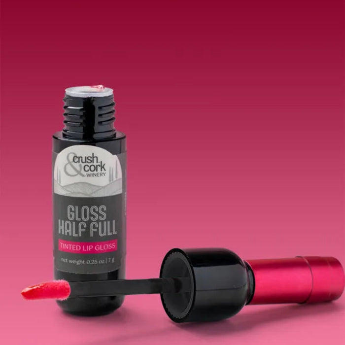 The Crush Crush & Cork Winery Gloss Half Full Tinted Lip Gloss delivers a glossy, ruby-colored finish that catches every light.