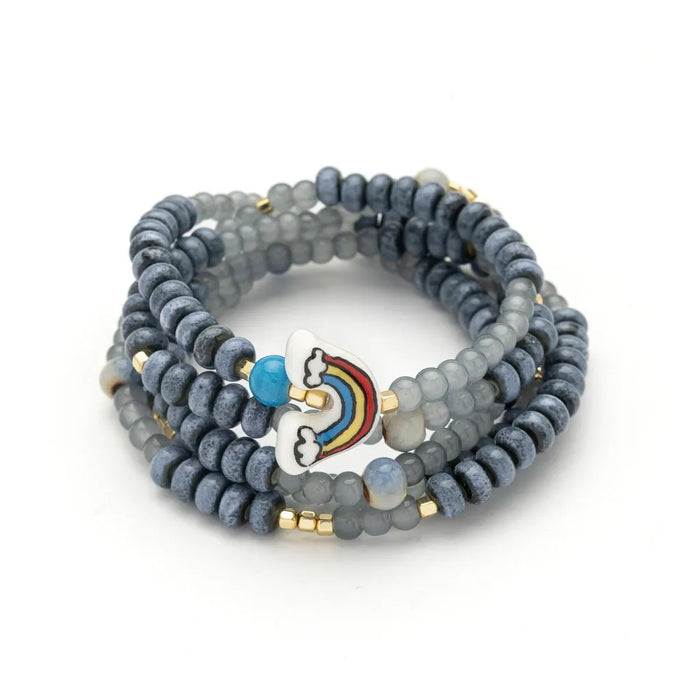 Scout Curated Wears Hope/Rainbow ceramic bead wrap bracelet and necklace with gray beads, gold-tone accents, and a colorful rainbow charm.