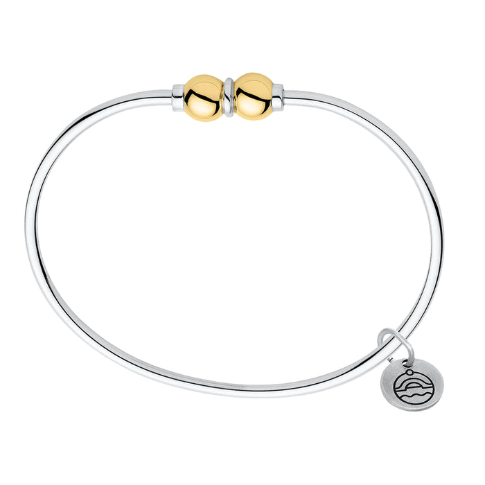 Silver bracelet with gold beads and a small round tag on a white background