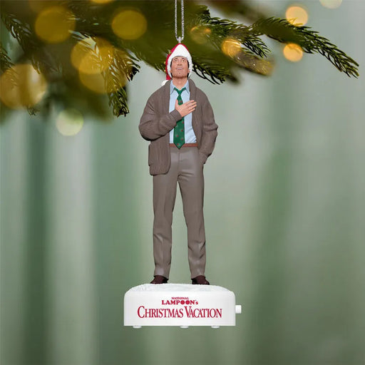 Clark Griswold ornament hanging on pine branch with bokeh lights featuring red Santa hat and green tie