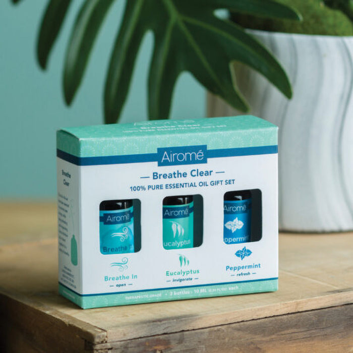 Airomé Breathe Clear essential oil gift set packaging on a wooden surface with a plant in the background.
