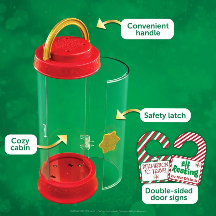 Red and clear elf  carrier with safety latch, cozy cabin, and convenient handle on a green background.