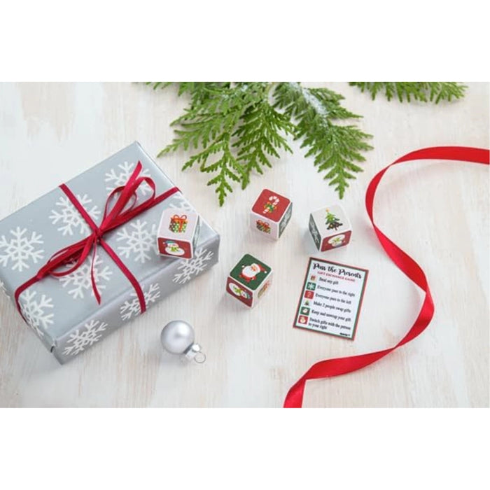 Christmas gift with red ribbon, snowflake-patterned paper, and decorative cubes on a light wooden surface.