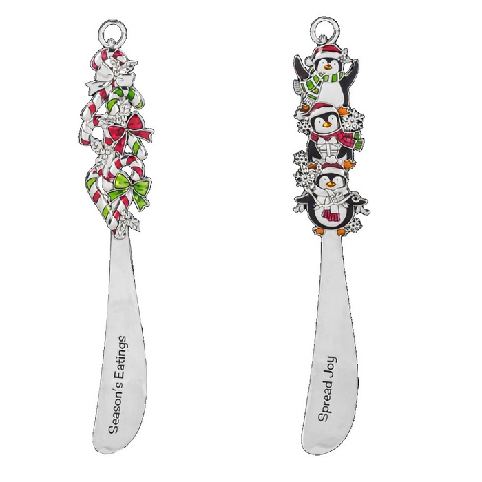 Two decorative butter knifes  with penguin and candy cane designs on a white background