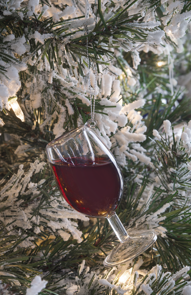 Decorative glass ornament filled with red liquid hanging on a snow-covered Christmas tree.