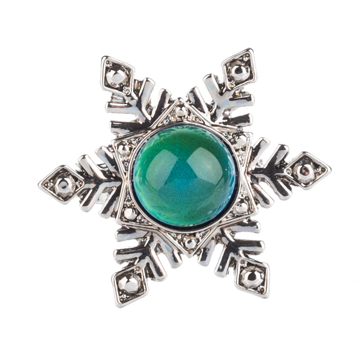 Silver snowflake-shaped brooch with a green gemstone on a white background
