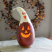 Decorative gourd with a carved face on a textured surface with a blurred background