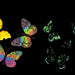 A set of glow-in-the-dark butterfly magnets  or decals displayed on a black background, with the text 'GOT GLOW?' in neon-style lettering at the top. The butterflies feature vibrant multicolor patterns, including yellow, green, blue, pink, and purple, with some shown glowing as bright green and cyan on the right.