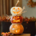 Stack of three carved pumpkins with glowing lights on a wooden surface.