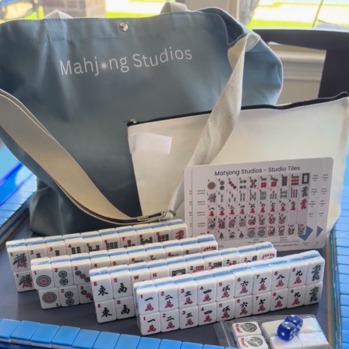 Mahjong set with tiles, dice, and packaging on a blue surface