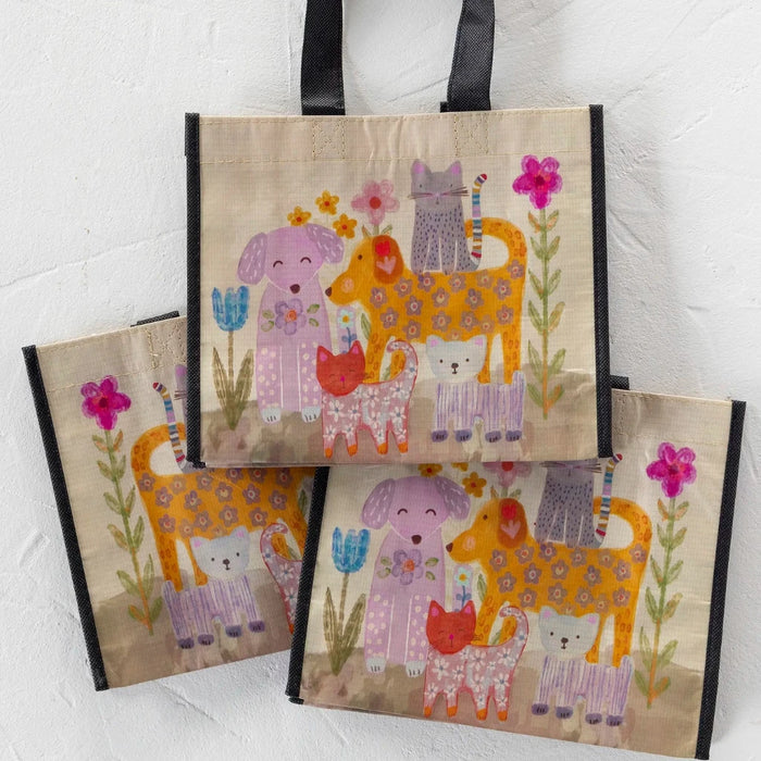 A hand is holding a cheerful bag that features colorful illustrations of cats and dogs.