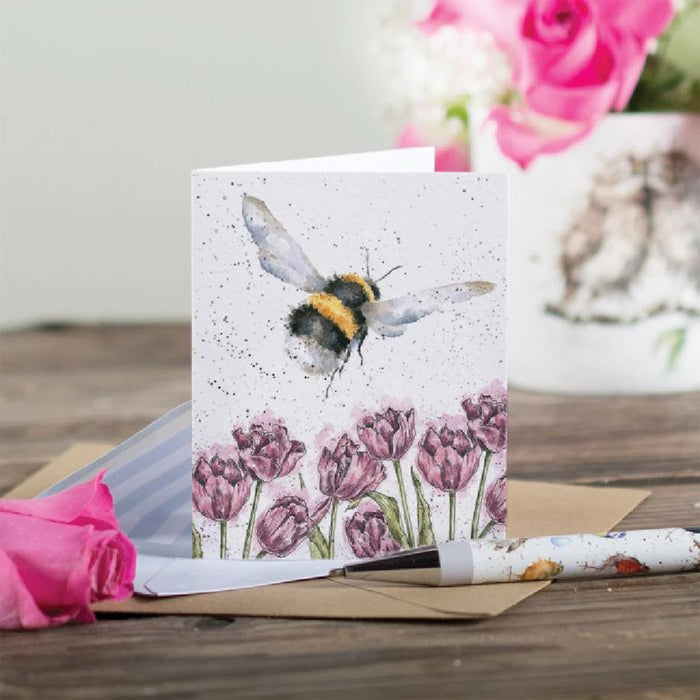 A colorful greeting card depicting a bee among blooming tulips, symbolizing spring and nature's beauty.