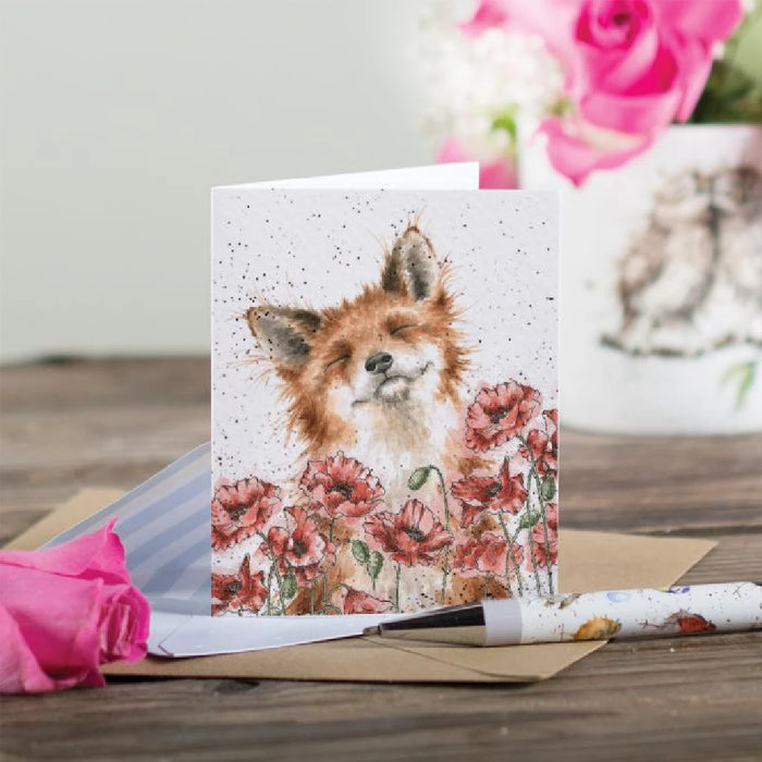 A charming card with a fox positioned in the middle, adorned with a variety of surrounding flowers.