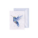 A greeting card featuring a colorful hummingbird in flight against a soft background.