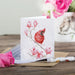 A vibrant red cardinal sitting on a branch, illustrated on a greeting card.
