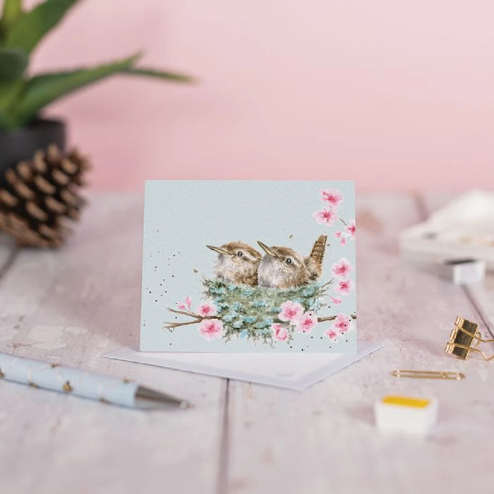 Two sweet birds in a nest illustrated on a greeting card, conveying warmth and friendship.
