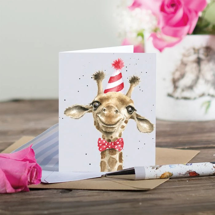 A giraffe sporting a festive birthday hat and a bow tie, adding a playful touch to a celebration.