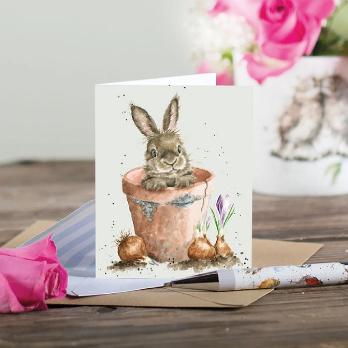 A charming card illustrating a bunny in a flower pot, adorned with various colorful flowers.
