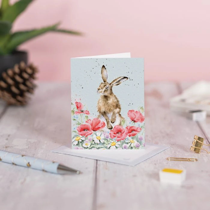 A decorative card displaying a rabbit sitting on vibrant flowers, evoking a sense of joy and nature's beauty.
