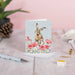 A decorative card displaying a rabbit sitting on vibrant flowers, evoking a sense of joy and nature's beauty.
