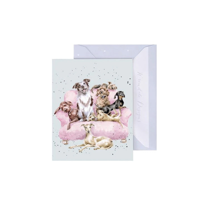 A greeting card featuring dogs sitting together on a pink couch, creating a cozy and playful atmosphere.