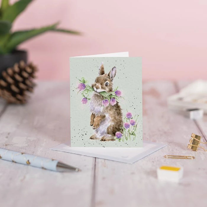 A card illustrated with a bunny and an array of blooming flowers.
