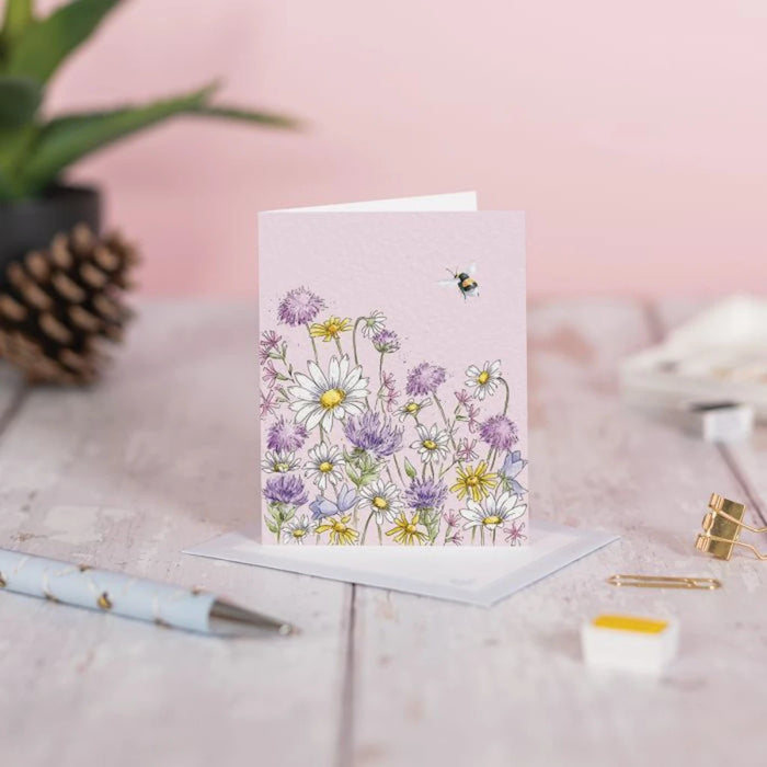  A decorative card showcasing a daisy flower with a bee perched on it, set against a gentle backdrop.
