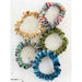 Four colorful scrunchies displayed on a white surface, showcasing a variety of vibrant hues and textures.