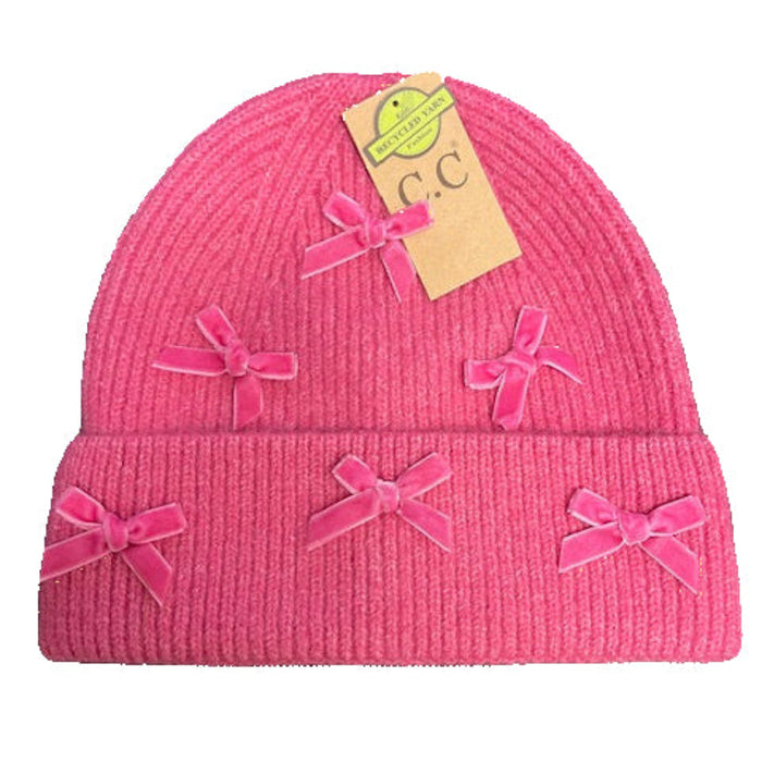 Pink knit beanie with bow details on a keyboard