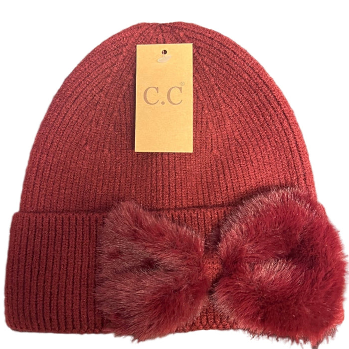 Red knit beanie with pom-poms on a desk next to a keyboard