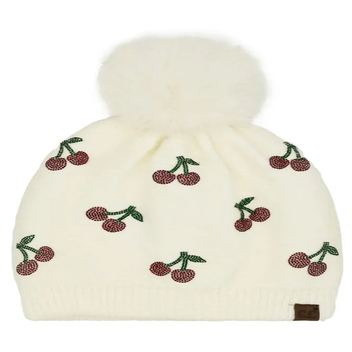 Ivory Cheveux Corp beanie with red rhinestone cherries, green stems, and a fluffy ivory pom-pom.