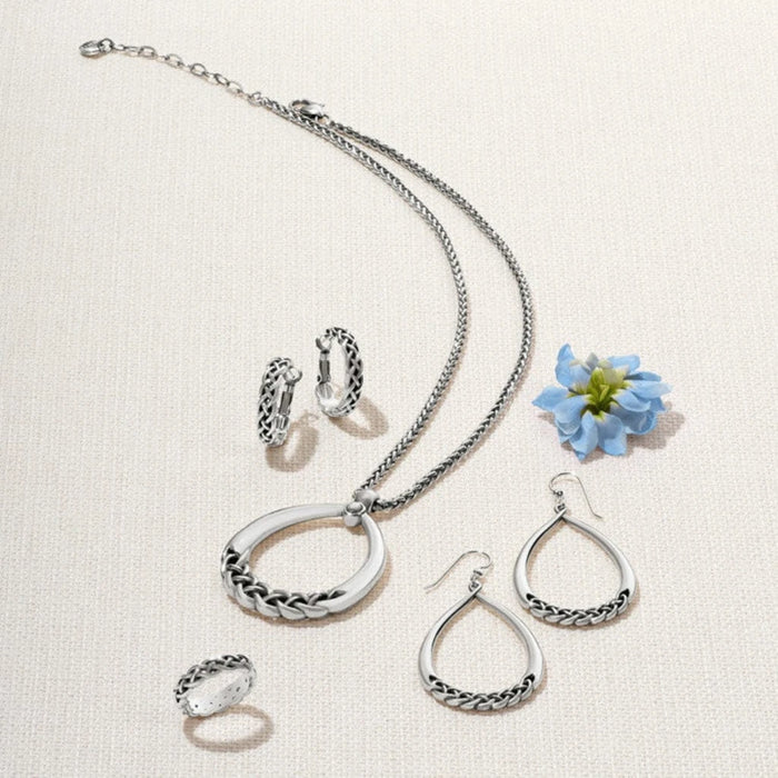 A pair of braided silver hoop earrings, reflecting light beautifully.