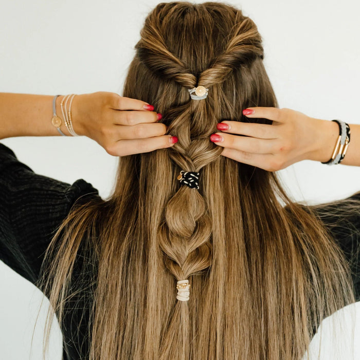Grey and black hair tie bracelet with a gold flower accent in an elegant Inspire design.