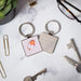 A square keychain displaying a bird motif in vibrant colors.