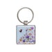 A square keychain displaying a bee and floral elements, emphasizing a nature-inspired theme.