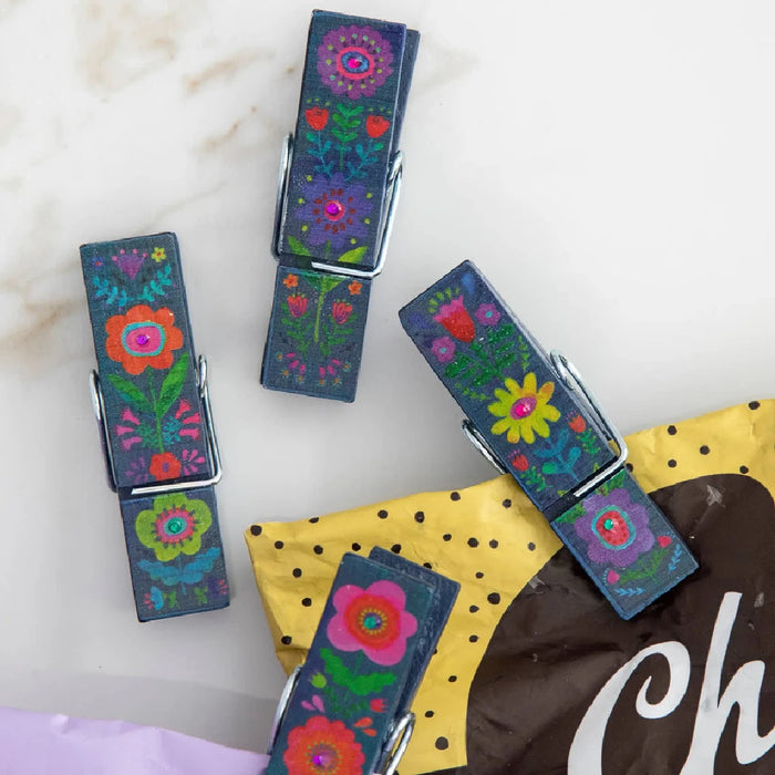 Three small clothespins adorned with colorful flowers, arranged neatly on a light background.