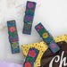 Three small clothespins adorned with colorful flowers, arranged neatly on a light background.