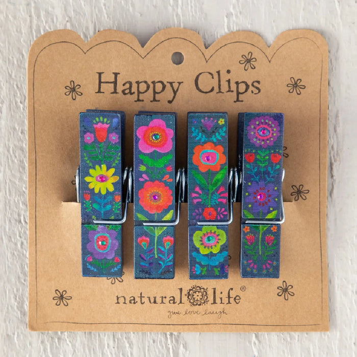 Three decorative clothespins featuring floral embellishments, set against a plain backdrop.
