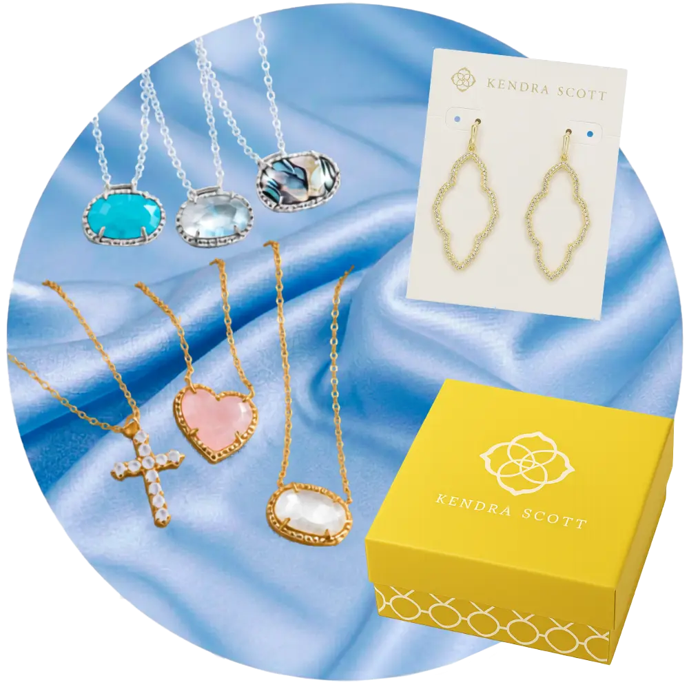 Jewelry set with necklaces and earrings on a blue satin background, featuring Kendra Scott branding.