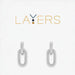 A pair of silver earrings featuring a delicate chain and a loop design, elegantly hanging from the earlobe.