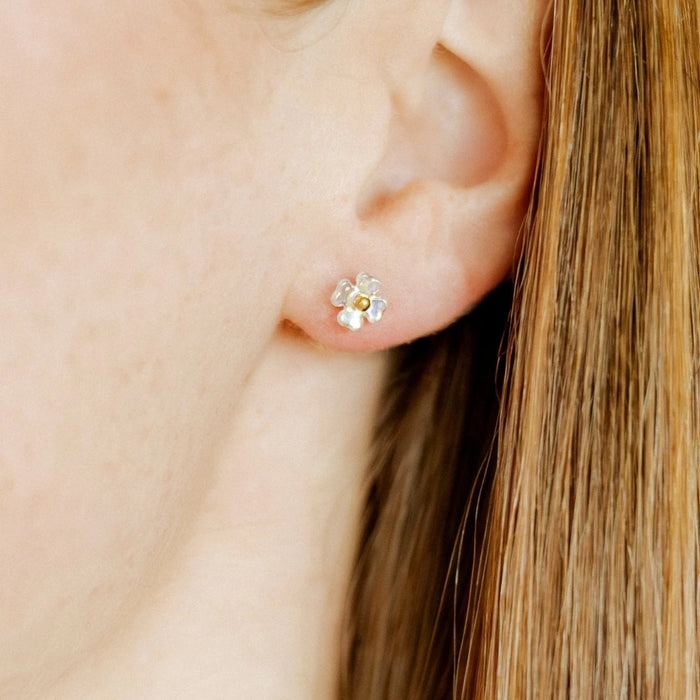 The Sloane Screwback Stud Earrings feature a translucent iridescent flower with a soft golden center, giving off a subtle glow from every angle. 