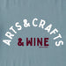 Close-up of Life Is Good Arts & Crafts & Wine graphic with distressed lettering on soft blue cotton fabric.