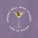 Graphic of a martini glass with green olives and the phrase "Drinks Well With Others" in white text, centered on a purple women's t-shirt with "Life Is Good" branding underneath.