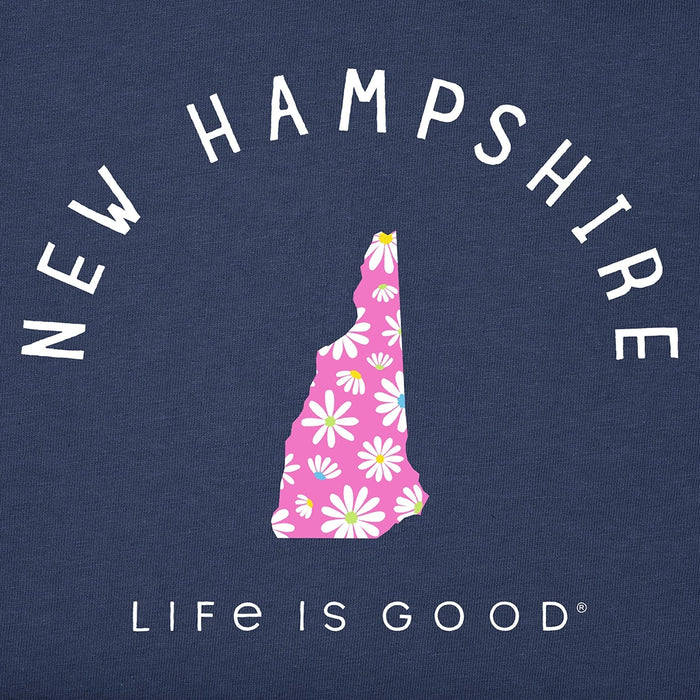 Close-up of Life Is Good Women’s NH Daisies Crusher Tee graphic showing pink New Hampshire state silhouette decorated with white and yellow daisies on navy fabric.