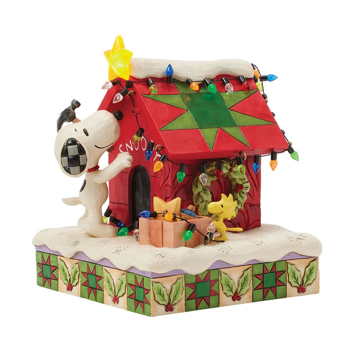 Snoopy decorating his red doghouse with Woodstock by his side, colorful Christmas lights, and a glowing Light-up yellow star on top.