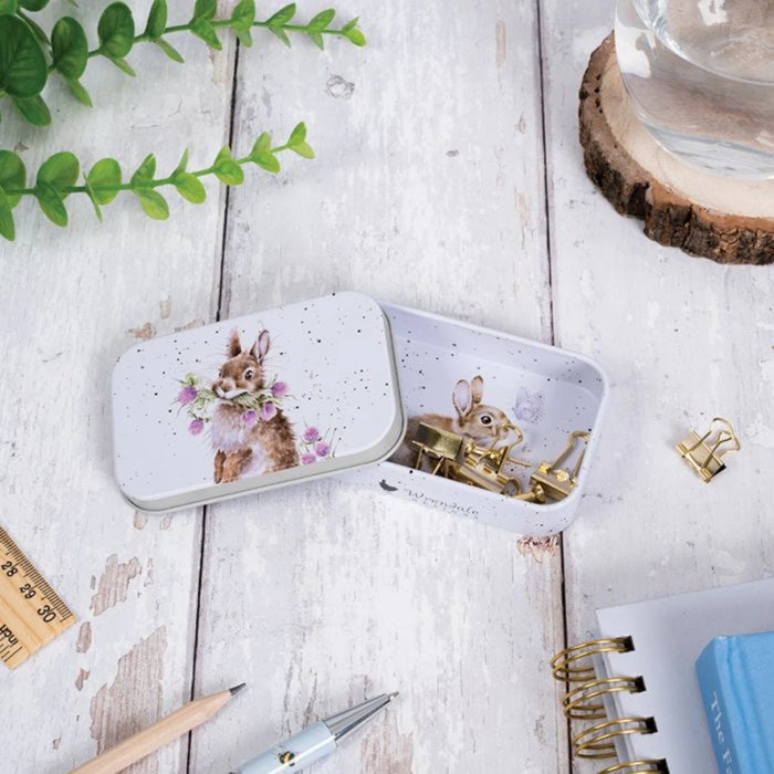 A white tin box with a playful bunny motif, perfect for storing trinkets or as a decorative piece.